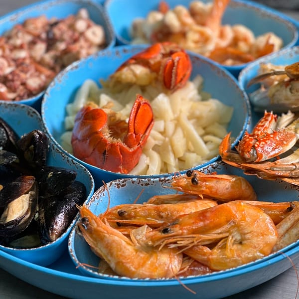 A blue platter with various seafood, including mussels, shrimp, lobster, and crab.