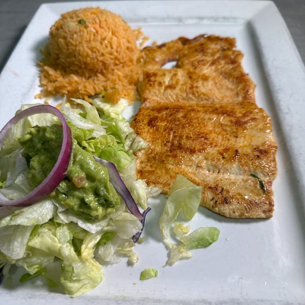 Grilled chicken with a side of Mexican rice, guacamole, and a fresh salad.