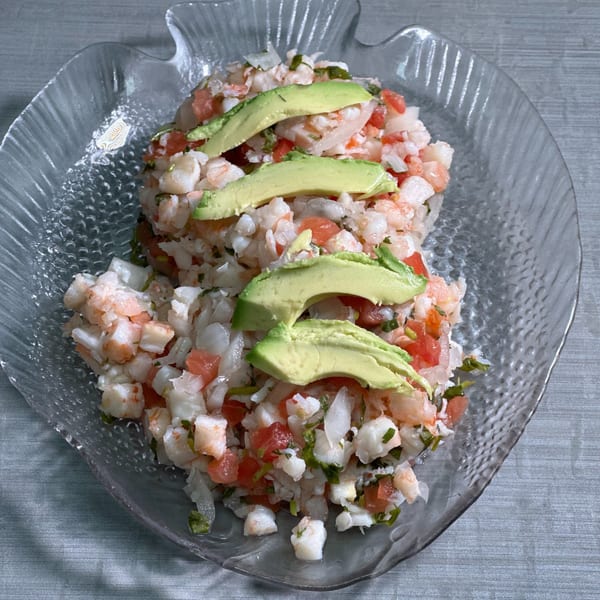 Mexican shrimp and fish ceviche with diced tomatoes, onions, cilantro, and avocado slices.